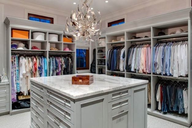 luxury walk-in closet with island and decorative lighting