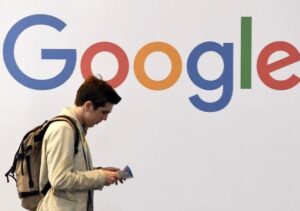 man walking past Google sign